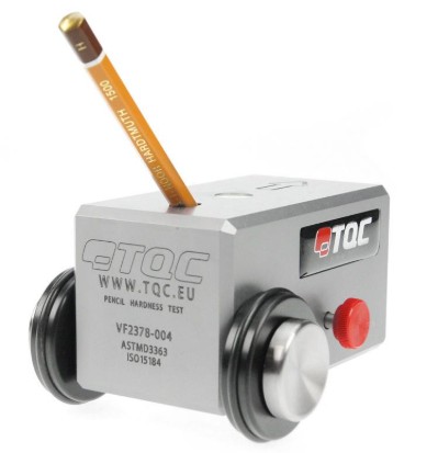 A TQC pencil hardness tester — a small wheeled block holding a calibrated pencil at a fixed angle