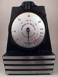 A Newman ST-1E mechanical screen tension meter: round dial gauge reading in newtons per centimeter, mounted on a three-bar measuring base