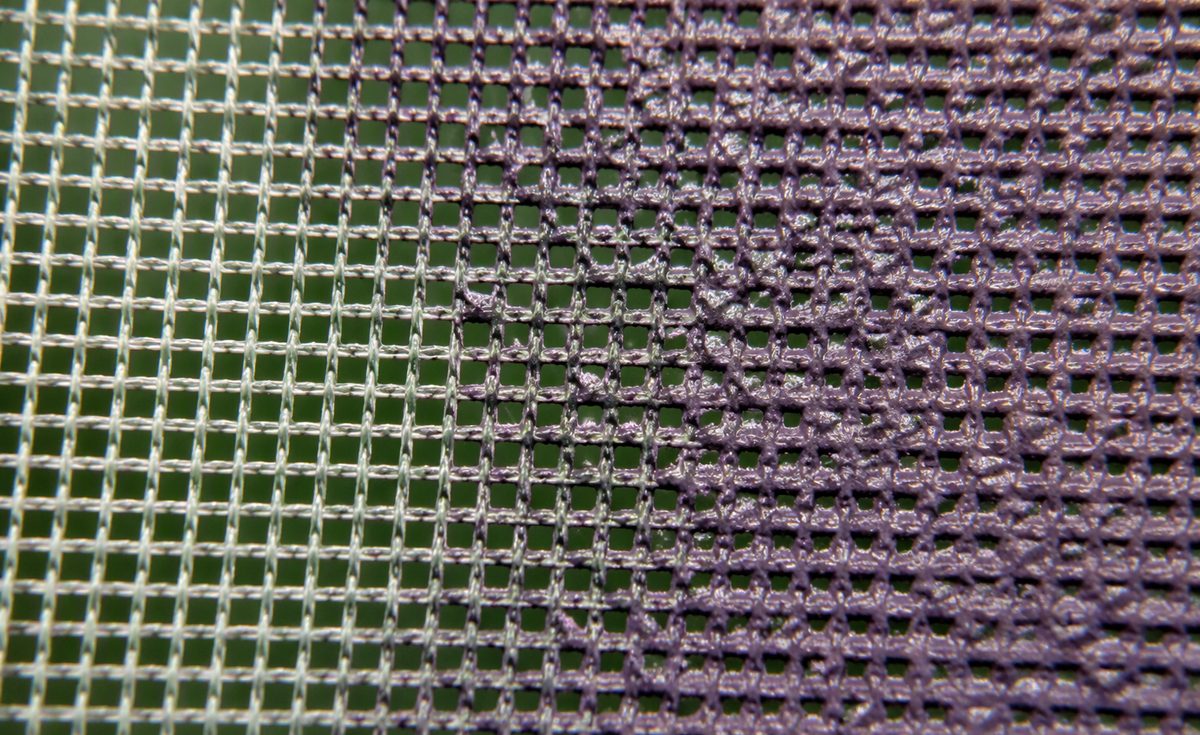 Macro photo of screen printing mesh with dried water-based ink clogging half of the mesh openings